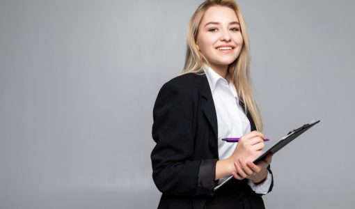 portrait-woman-holding-clip-board-hands-writing-paper-wearing-glasses-isolated-grey-wall